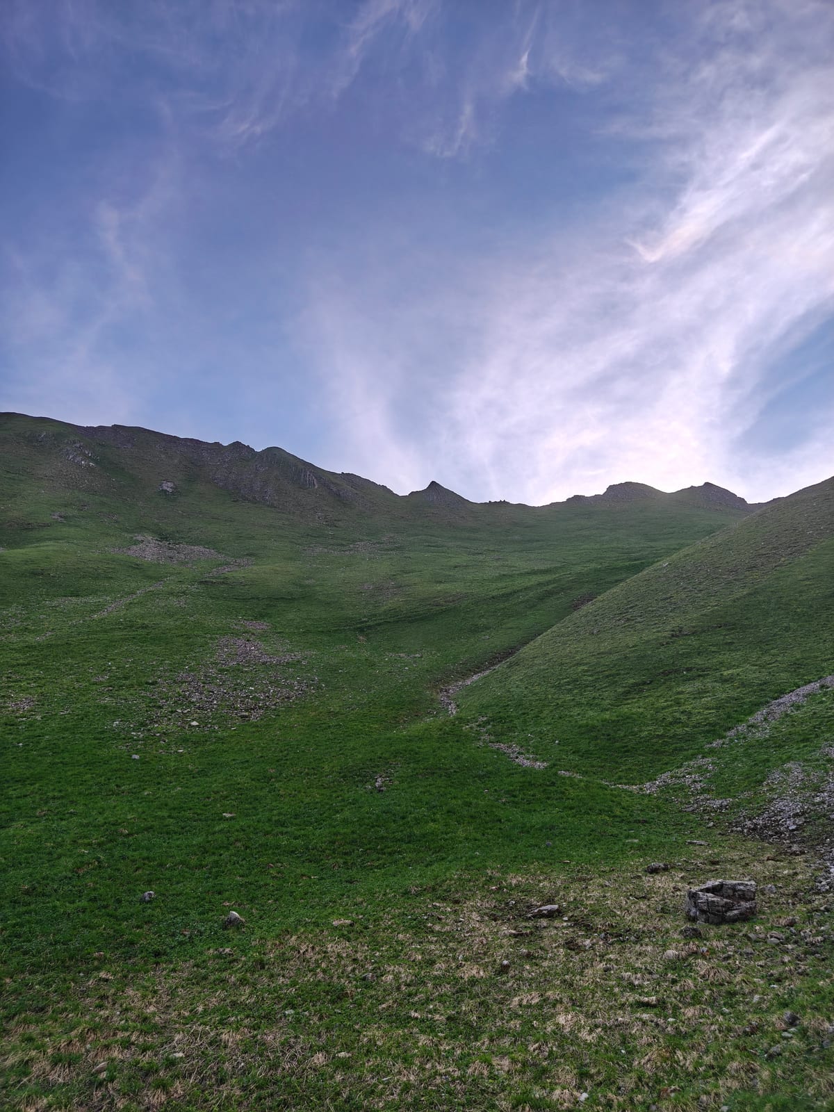 Open grass slope climbing toward a rocky ridge crest