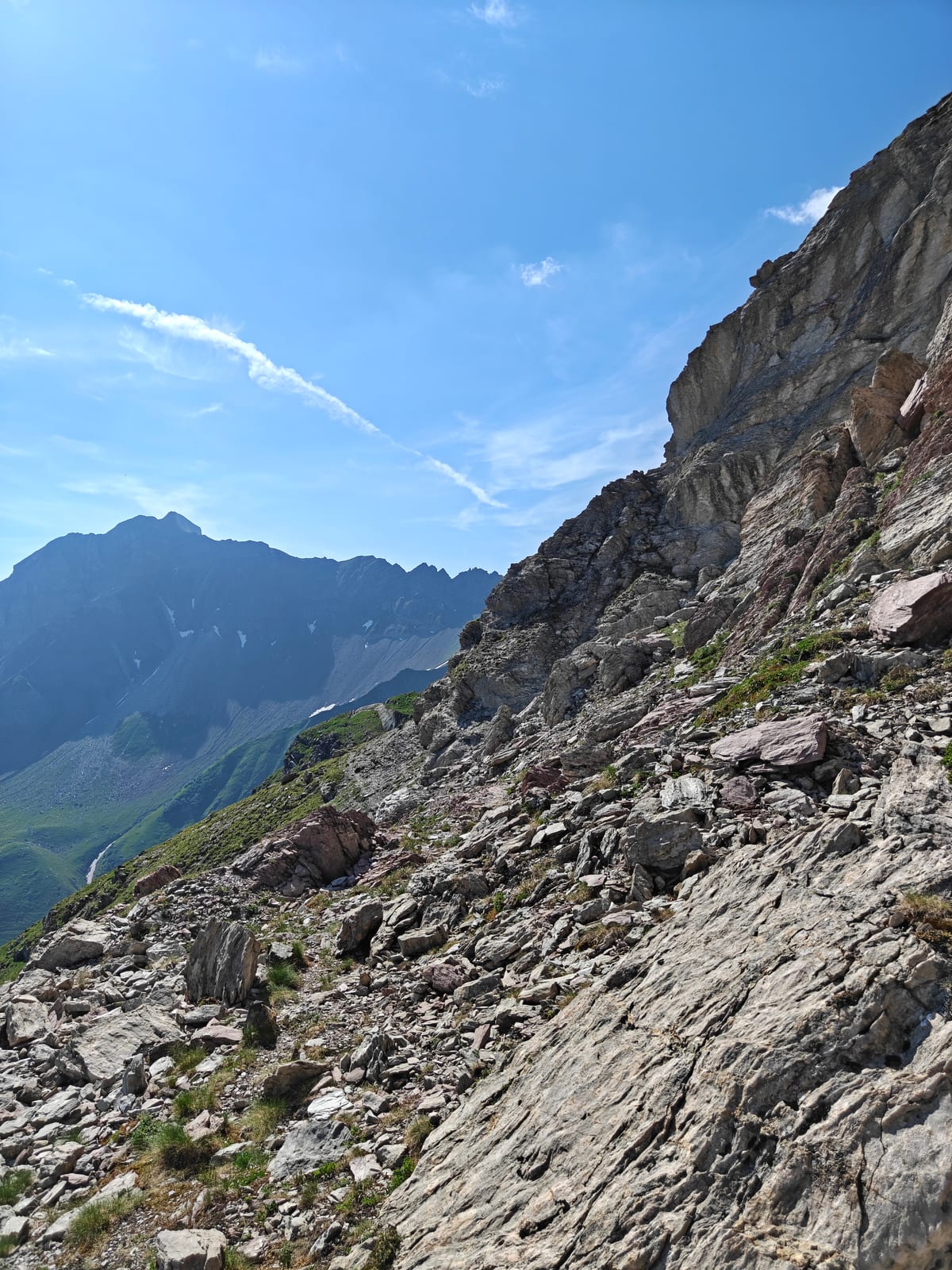 Rocky traverse with a distant peak visible, just below the grass tongue