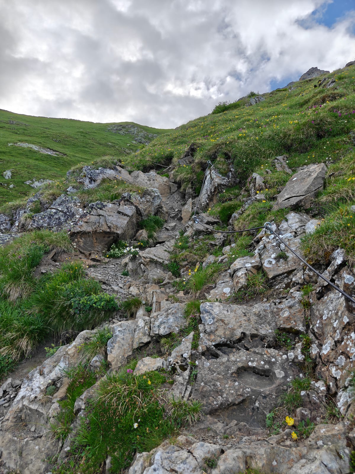 Rocky gully with a fixed steel cable running through broken limestone