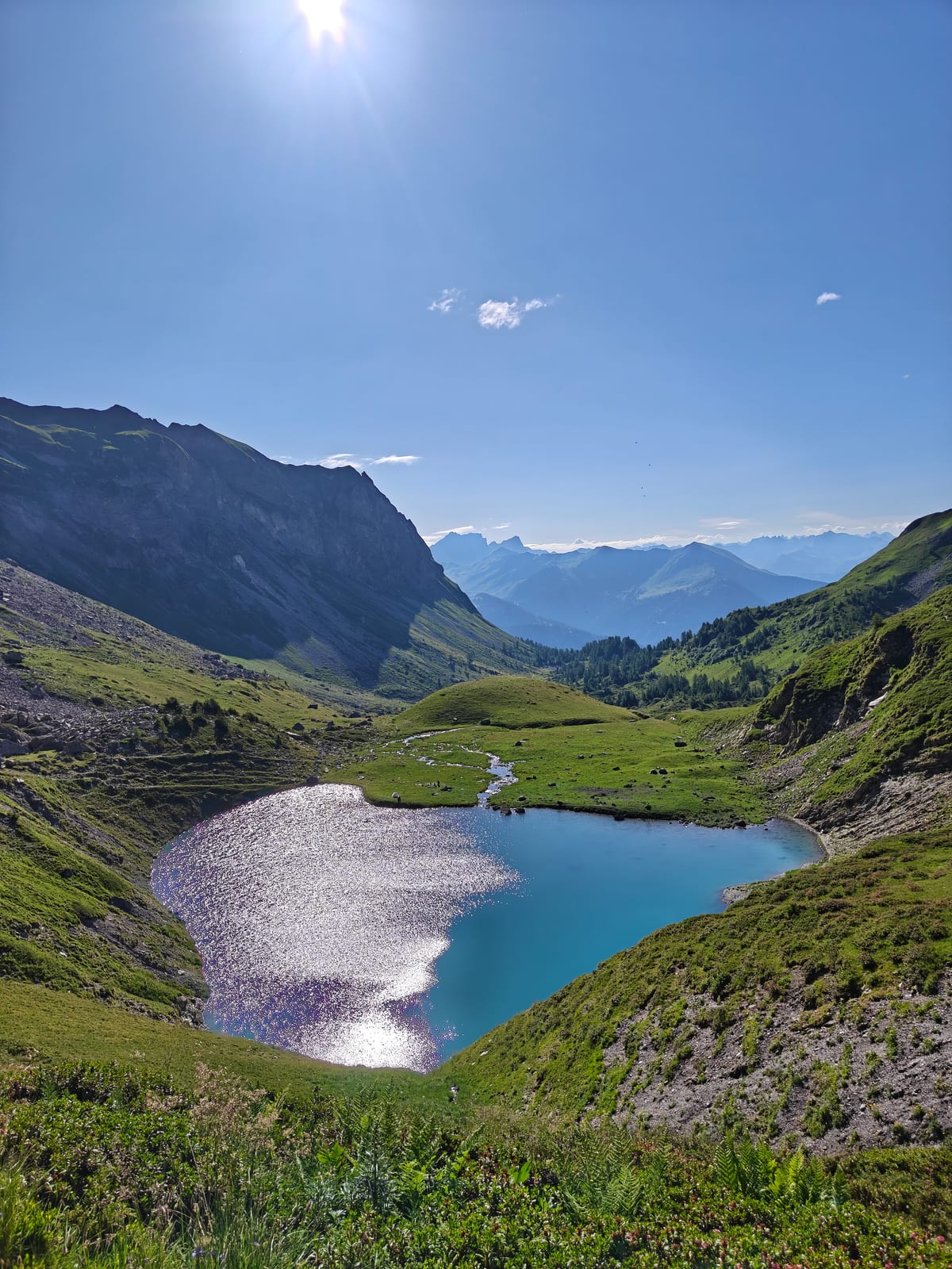 Small turquoise alpine lake in a green basin surrounded by mountains
