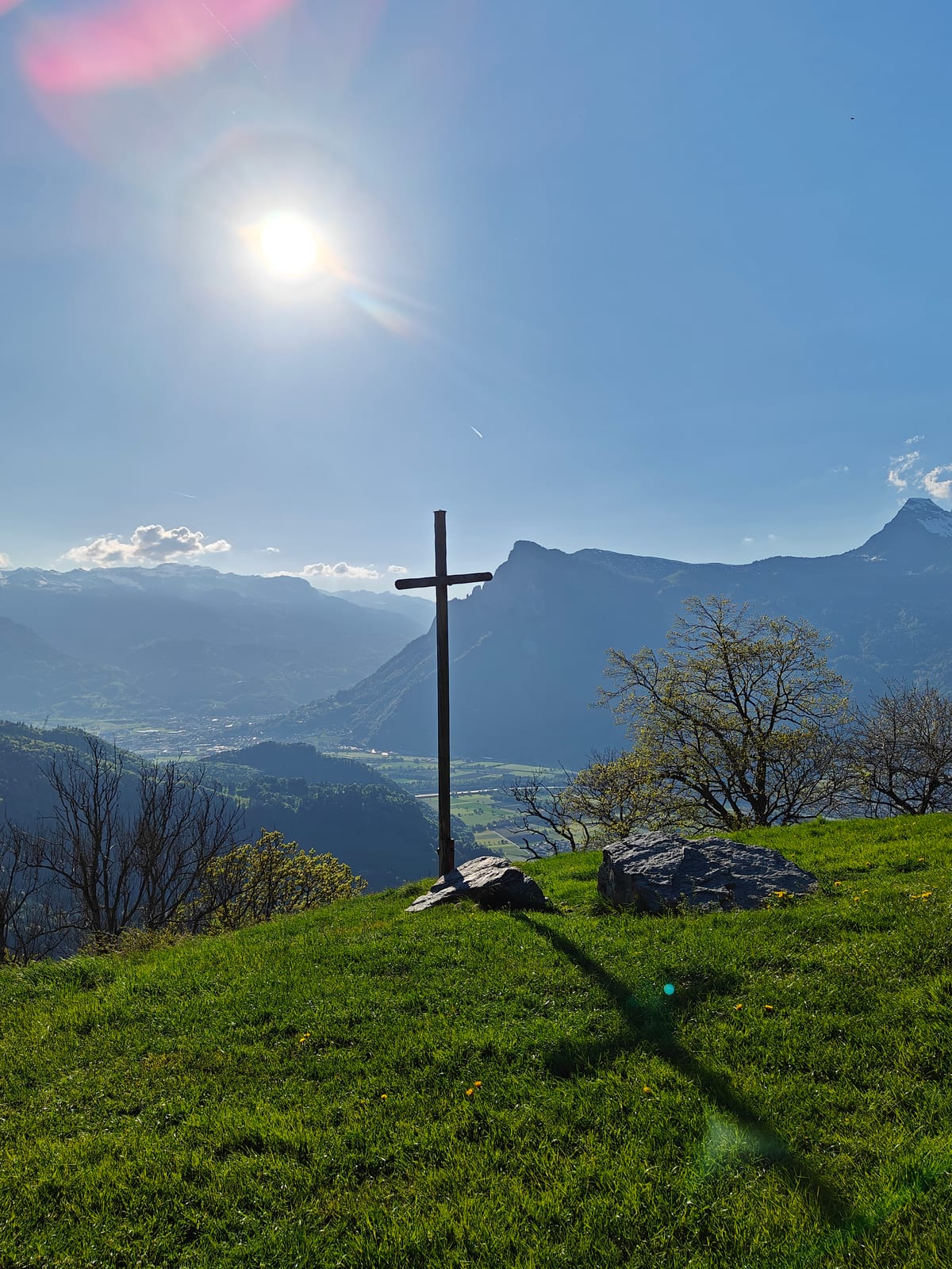 The summit cross at Guscha with the Rhine Valley and Alps behind