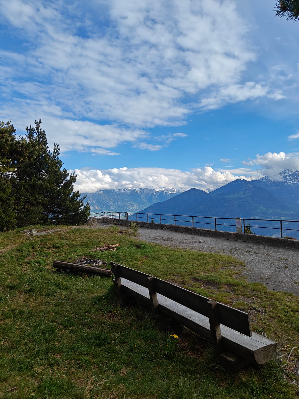Summit viewing platform with bench and safety railing, Alps in background